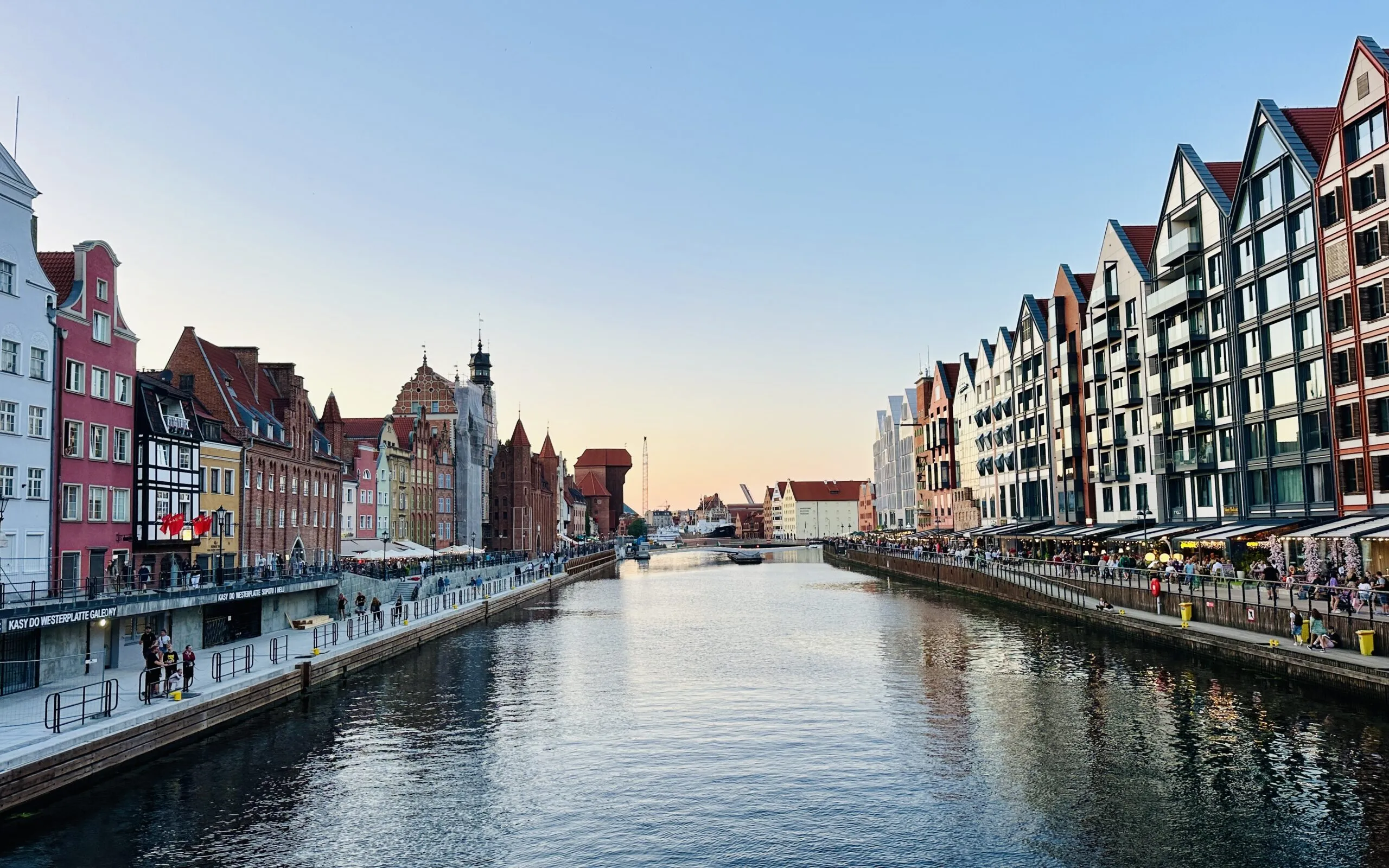 The Motława at sunset, the historic waterfront along one bank and modern gabled apartments along the other