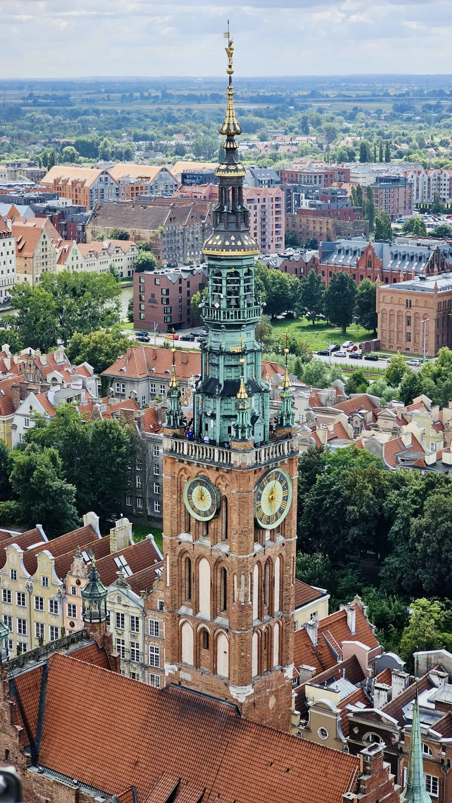 Looking down on the Main Town Hall tower, its green copper spire and gold clock faces above the red-tiled roofs of the old town